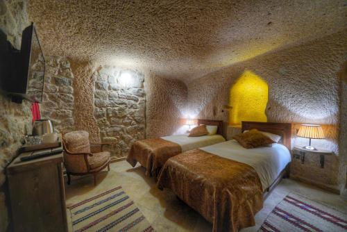 a bedroom with two beds and a stone wall at Takaev Cave House in Uchisar