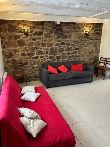 un divano rosso in un soggiorno con muro di mattoni di GITE INDEPENDANT en duplex proche mer COTE DE GRANIT ROSE a Pleubian