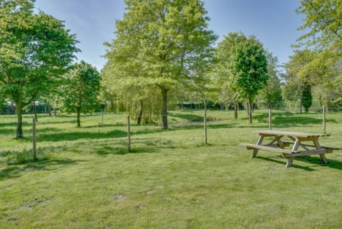 a wooden picnic table in a field with trees at Domein Den Buiten Bed And Breakfast DnD in Sint-Niklaas