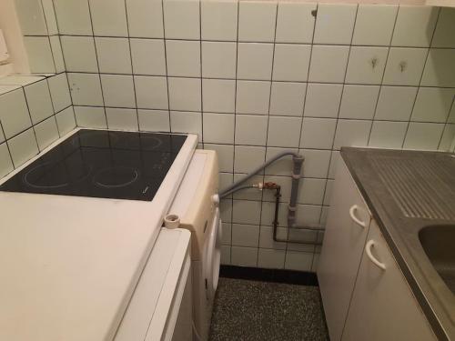 a kitchen with a stove in a white tiled wall at Sunny in Antwerp