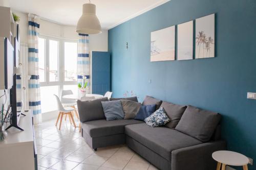 ein Wohnzimmer mit einem Sofa und einer blauen Wand in der Unterkunft Ad un passo dal molo con 2 biciclette incluse in Viareggio