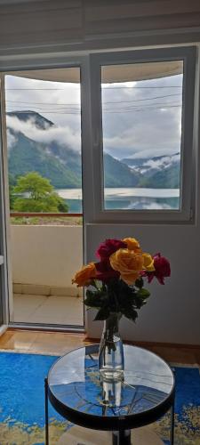 a vase of flowers sitting on a glass table at Apartment Lake story in Pluzine