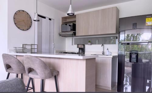 a kitchen with a counter and two chairs and a clock at Stunning, Brand-new Apartment in Santa Fe de Antioquia