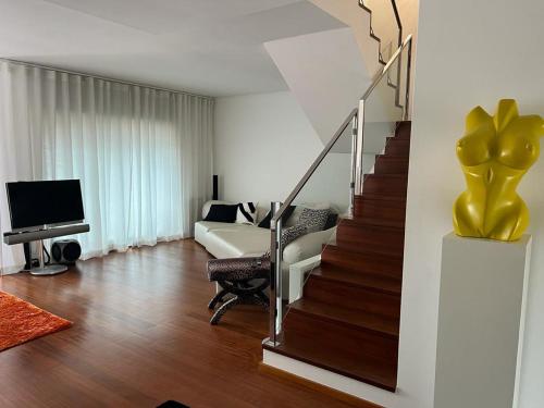 a living room with a staircase with a couch and a television at Vela Marina, Costa Nova in Gafanha da Encarnação