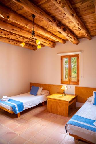 two beds in a room with wooden ceilings at Siamoformentera Villa Beatrice in Playa Migjorn