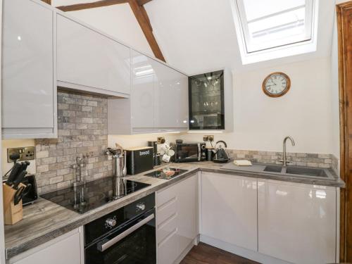 a kitchen with white cabinets and a clock on the wall at The Nest in Nuneaton