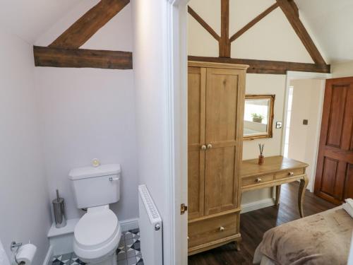 a bathroom with a toilet and a wooden cabinet at The Nest in Nuneaton