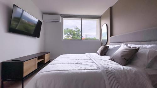a white bedroom with a large bed and a television at Stunning, Brand-new Apartment in Santa Fe de Antioquia