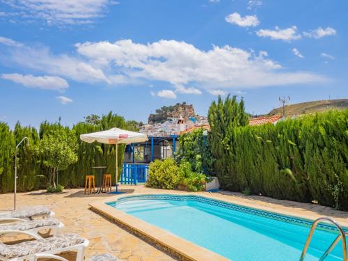 une piscine avec des chaises et un parasol ainsi qu'une maison dans l'établissement Cubo's La Casa del Abuelo, à Ardales