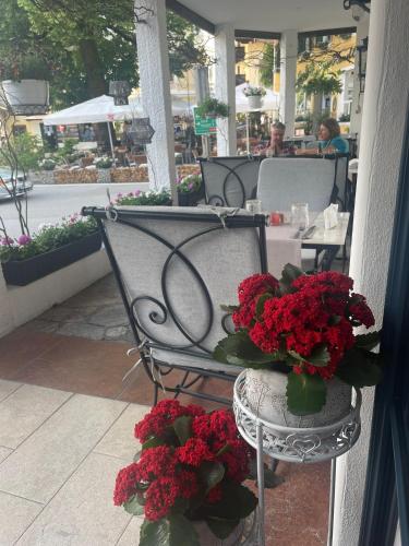 a metal bench with red flowers on a patio at Hotel Radetzky in Sankt Gilgen