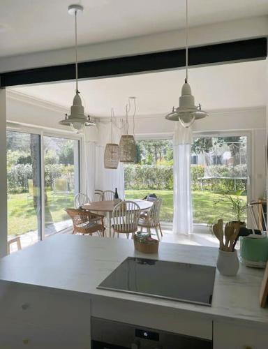 une cuisine avec une grande fenêtre et une table avec des chaises dans l'établissement Le Rosa: Villa de charme entre mer et pinède, à Quend