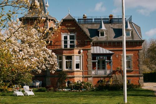 a large brick house with white chairs in front of it at Aggershøj pensionat in Marstal