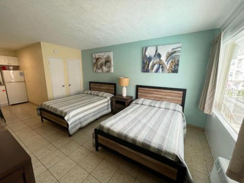 a bedroom with two beds and a kitchen with a refrigerator at Beach Colony Motel in Wildwood Crest