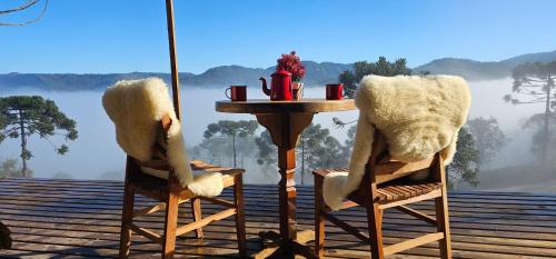 a table with two chairs and a table with a view at Sunset Serrano Chalés in Urubici