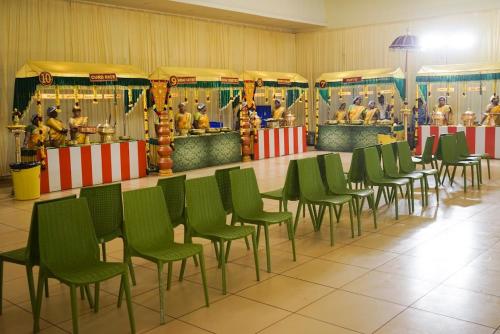 a group of green chairs in a room with a carousel at Dwarka Palace Luxury Rooms, Madurai - Trichy Bye Pass, Madurai in Madurai