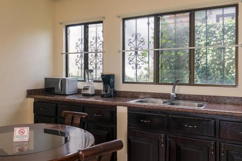 a kitchen with a sink and a table and windows at Hotel Mar de Luz in Jacó