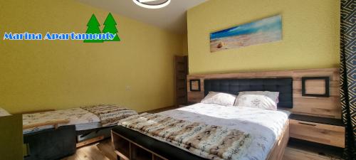2 camas en una habitación con paredes amarillas en Marina Apartamenty, en Rozewie