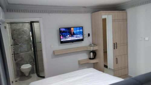 TİOS OTEL في زونجولداك: غرفة نوم بسرير وتلفزيون على جدار