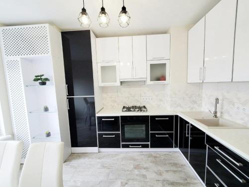 a kitchen with white cabinets and black appliances at Prospekt in Chernivtsi