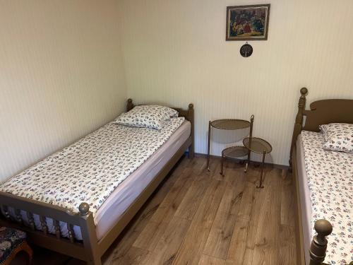 a bedroom with two beds and a wooden floor at Arbatinės apartamentai - Močiutės namelis in Biržai