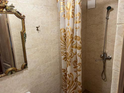 a shower with a shower curtain and a mirror at Arbatinės apartamentai - Močiutės namelis in Biržai