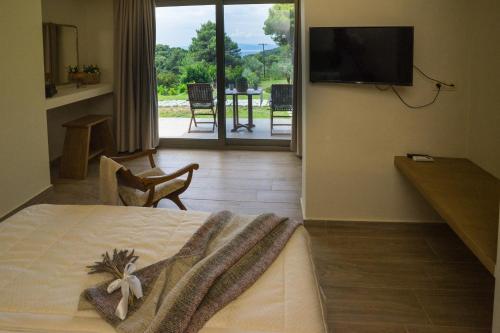 a bedroom with a bed and a television and a patio at Forest Resort Suites Skiathos in Troulos