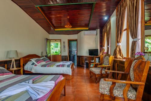 a room with three beds and chairs and a television at Hotel Mar de Luz in Jacó