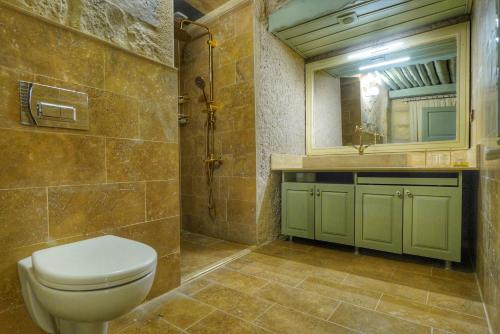 a bathroom with a toilet and a sink and a mirror at Takaev Cave House in Uchisar