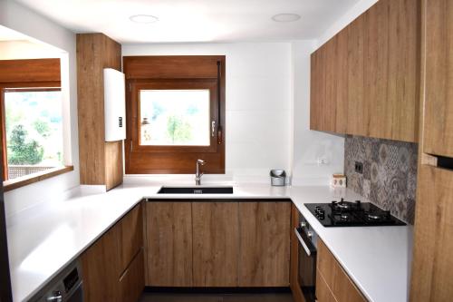une cuisine avec des comptoirs blancs et des armoires en bois dans l'établissement Apartamento Tubal, à Bossost