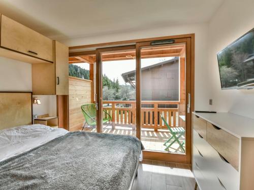 une chambre avec un lit et un balcon dans l'établissement Le Génépi - Superbe T2 cabine 4-6 pers, neuf, à 50m des pistes, avec balcon, garage et WiFi - FR-1-685-67, aux Gets