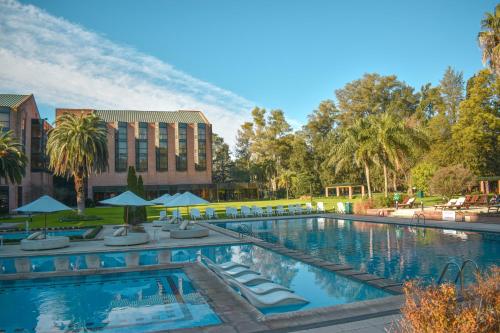 una piscina en un complejo con sillas y sombrillas en Sheraton Pilar Hotel & Convention Center en Pilar