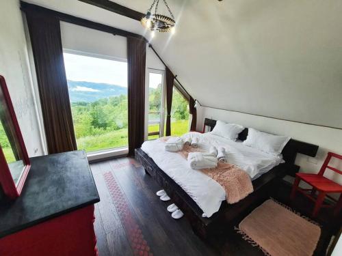 ein Schlafzimmer mit einem großen Bett und einem großen Fenster in der Unterkunft Emoția Munților 