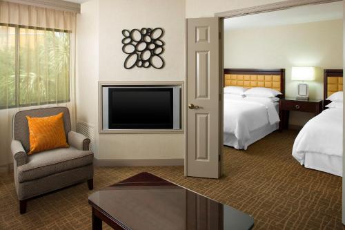 a hotel room with a television and a bed at Sheraton Suites Orlando Airport Hotel in Orlando