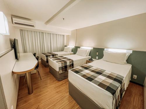 a hotel room with two beds and a desk at St Paul Plaza Hotel in Brasilia