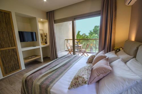 um quarto com uma cama, uma televisão e uma varanda em Forest Resort Suites Skiathos em Troulos