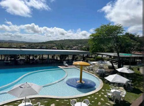 格雷夫森德的住宿－Flat Fazenda Monte Castelo Gravatá，一个带遮阳伞和桌椅的大型游泳池