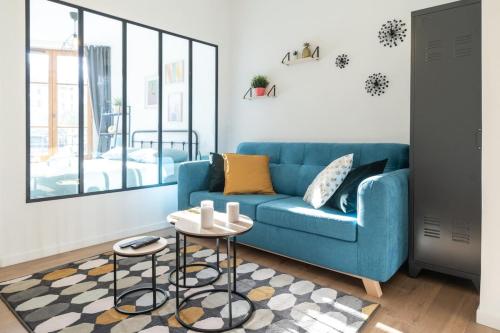 un salon avec un canapé bleu et une table dans l'établissement The TANNEURS - Charming 6-person apartment - Steps from Valmy Metro, à Lyon