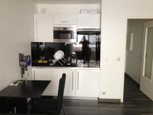 une cuisine avec des armoires blanches, une table et un micro-ondes dans l'établissement Juana, à Antibes