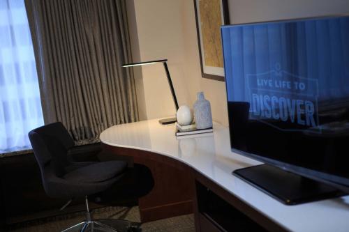 Renaissance Seattle Hotel في سياتل: مكتب فيه تلفزيون وكرسي ومصباح