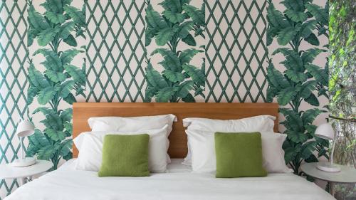 a bed with white sheets and green pillows at Home Hotel in Buenos Aires