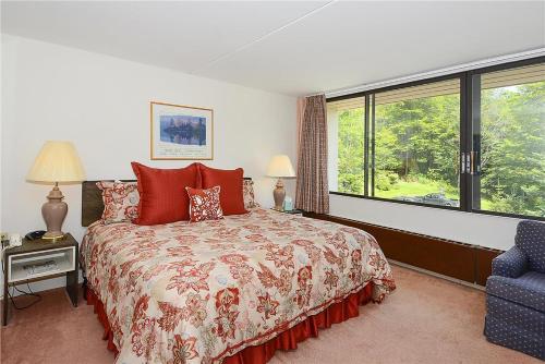 Un dormitorio con una cama con almohadas rojas y una ventana en Notchbrook 24AB en Stowe