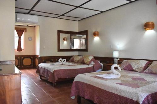 a hotel room with two beds and a swan on it at Hotel Mar de Luz in Jacó