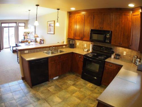 a kitchen with wooden cabinets and a black stove top oven at Woodhaven #16 By Bear Country in Sun Peaks