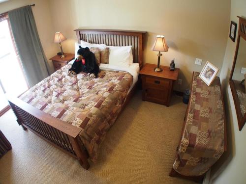a black dog sitting on a bed in a bedroom at Woodhaven #16 By Bear Country in Sun Peaks