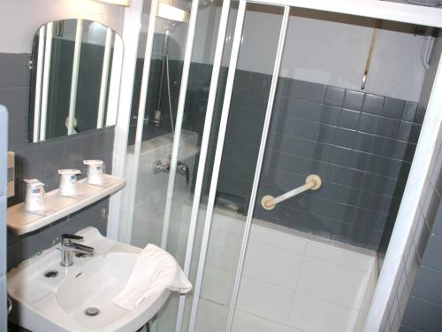 uma casa de banho com um chuveiro, um lavatório e um espelho. em Hotel Du Gave em Lourdes