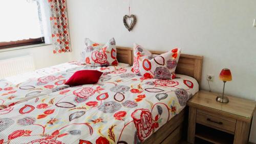 a bed with a flowered comforter and pillows at Ferienwohnung am Dorfplatz in Waldkappel