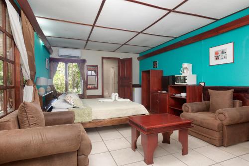 a bedroom with a bed and a couch and a table at Hotel Mar de Luz in Jacó