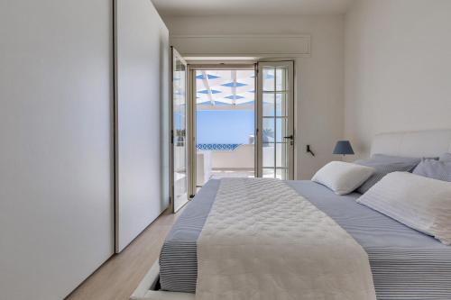 a white bedroom with a large bed and a balcony at L'Attico di Alessia by BarbarHouse in Maruggio