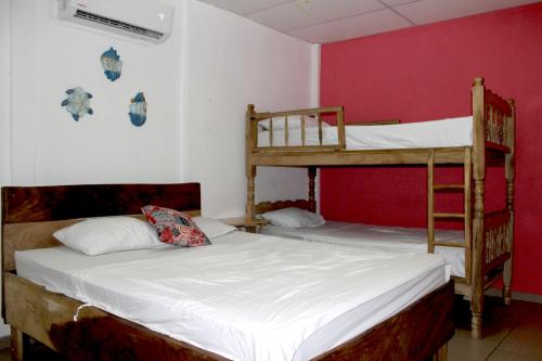 2 Etagenbetten in einem Zimmer mit einer roten Wand in der Unterkunft Kali Hostal in La Libertad