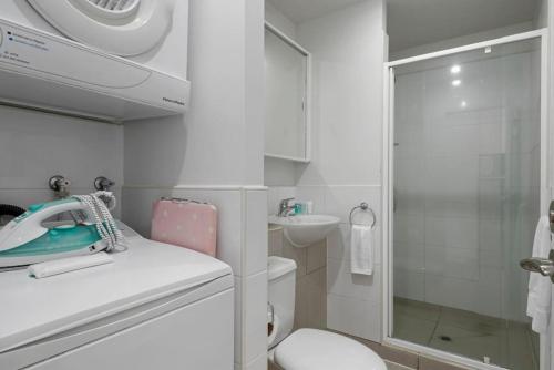 y baño blanco con lavabo y ducha. en Gorgeous Cityscape Apartment in Auckland's CBD, en Auckland